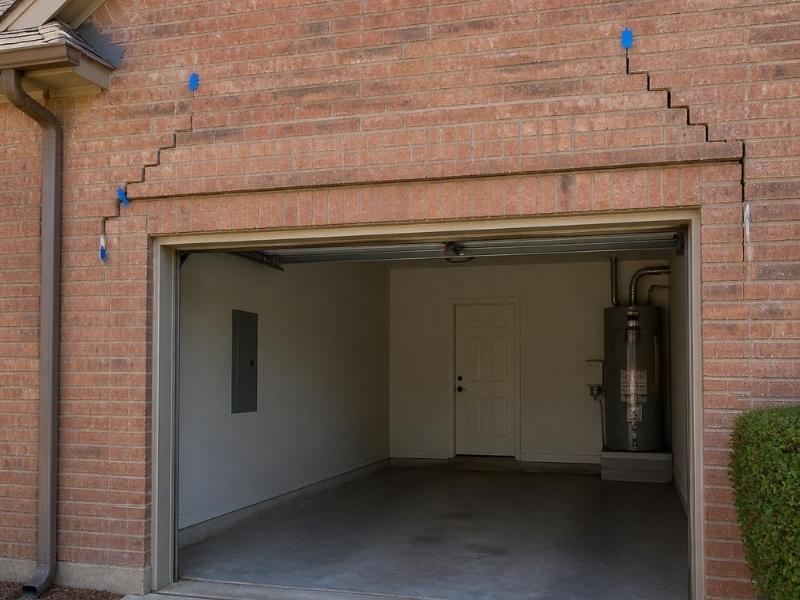 Stair-step cracks in brick masonry above a residential garage opening in Fort Worth, Texas.
