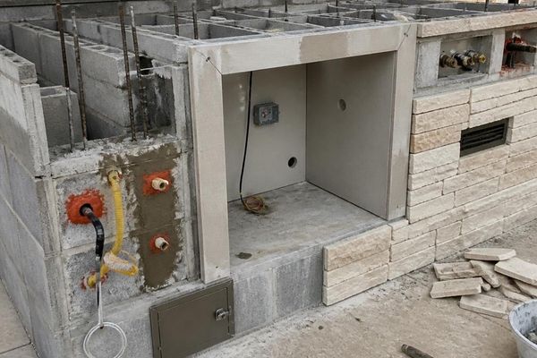 Outdoor kitchen masonry installation with reinforced block walls, utility openings, ventilation, and stone veneer in Fort Worth, Texas.