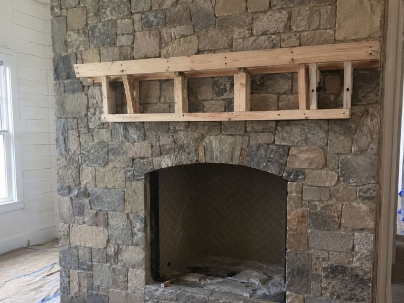 Stone fireplace with a wood mantel support frame installed during a custom interior renovation project.
