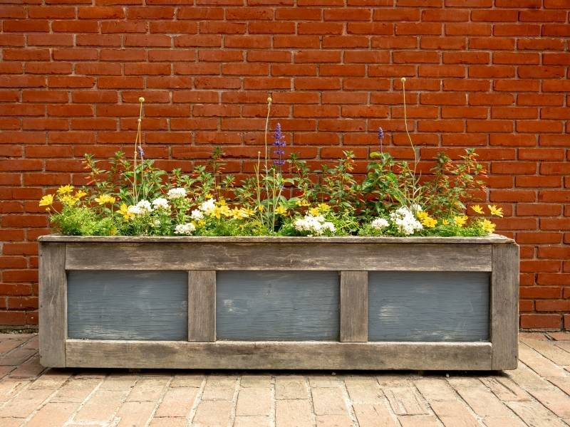 Brick masonry planter with drainage outlets and landscaping beside an exterior brick wall in Fort Worth, Texas
