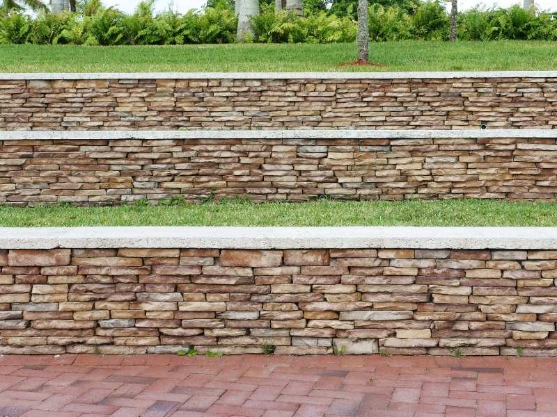 Stone mason building layered natural stone garden seat walls in Frisco, Texas, with level seating caps, stable foundations, and terraced planting areas.
